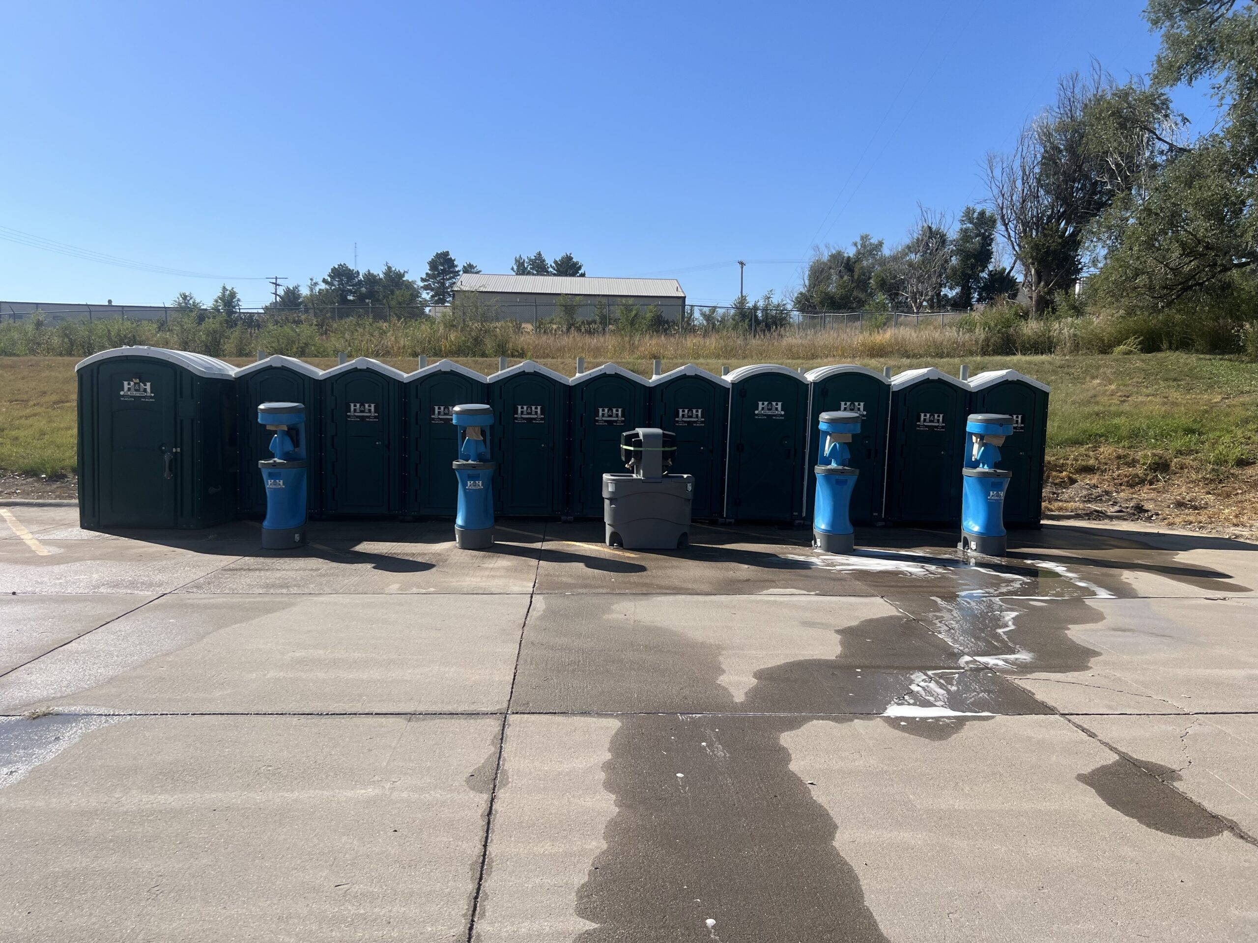 Green Porta Pottys and Handwashing stations Green Porta Pottys and Handwashing Stations in a parking lot in front of a field in Western Kansas.